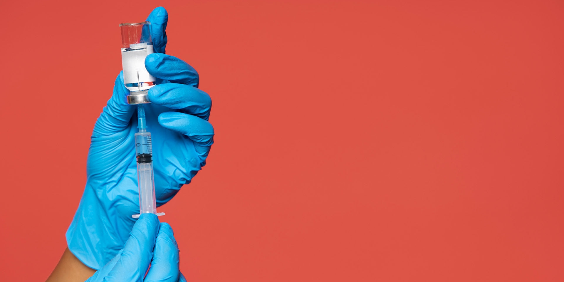 Person with sterile gloves withdrawing a vaccine solution