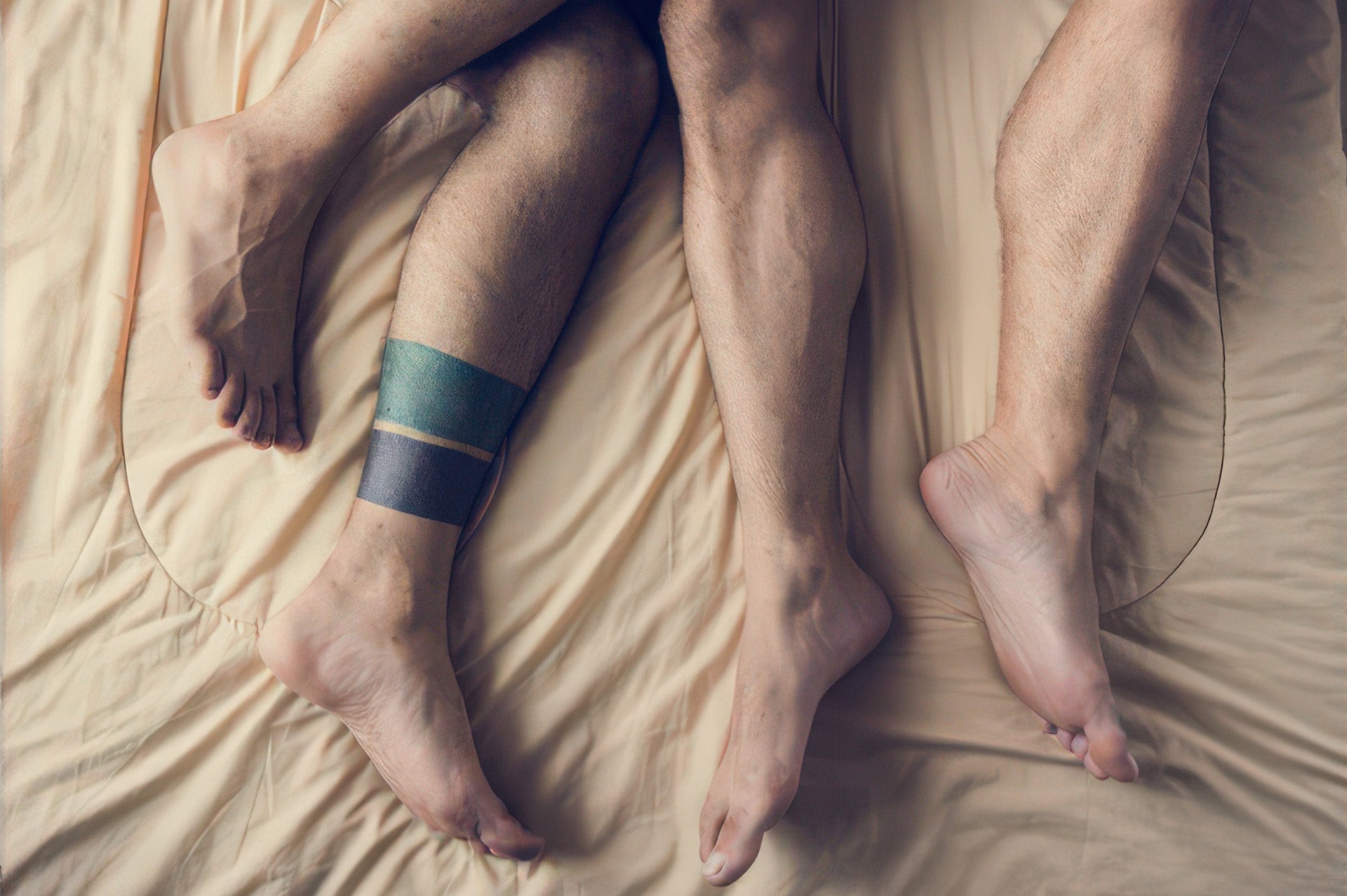 Couple lying in bed with legs intertwined, conveying intimacy and connection