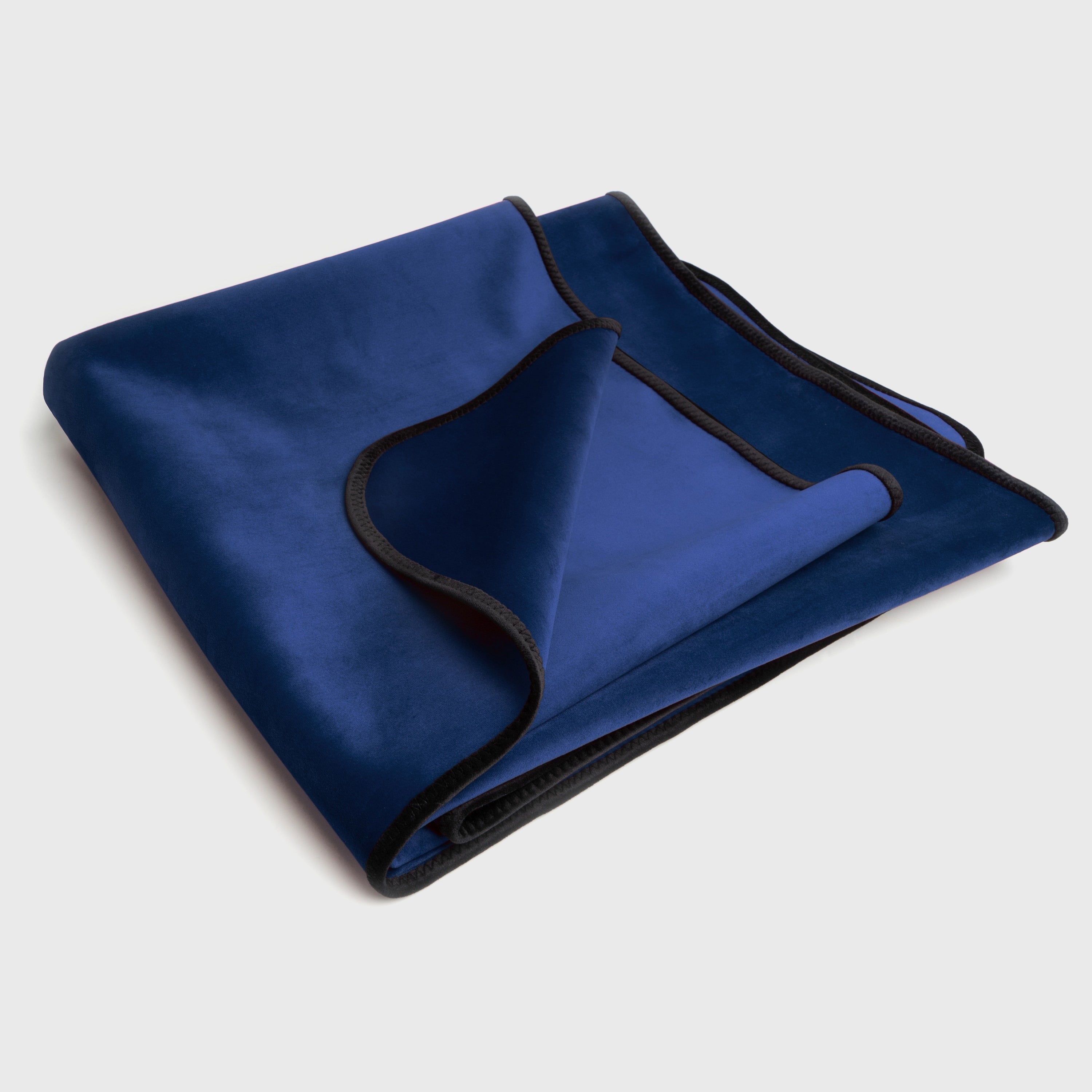 Folded blue blanket with black trim on a light gray background