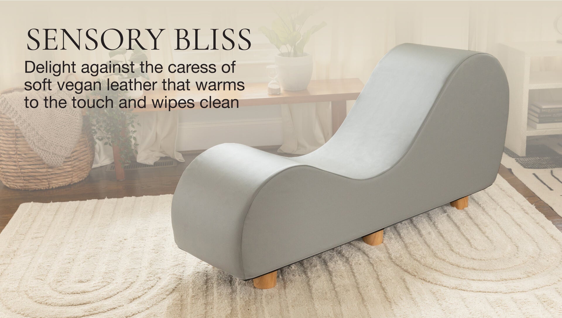 Gray lounge chair with wooden feet on a light wood floor, text about soft vegan leather.