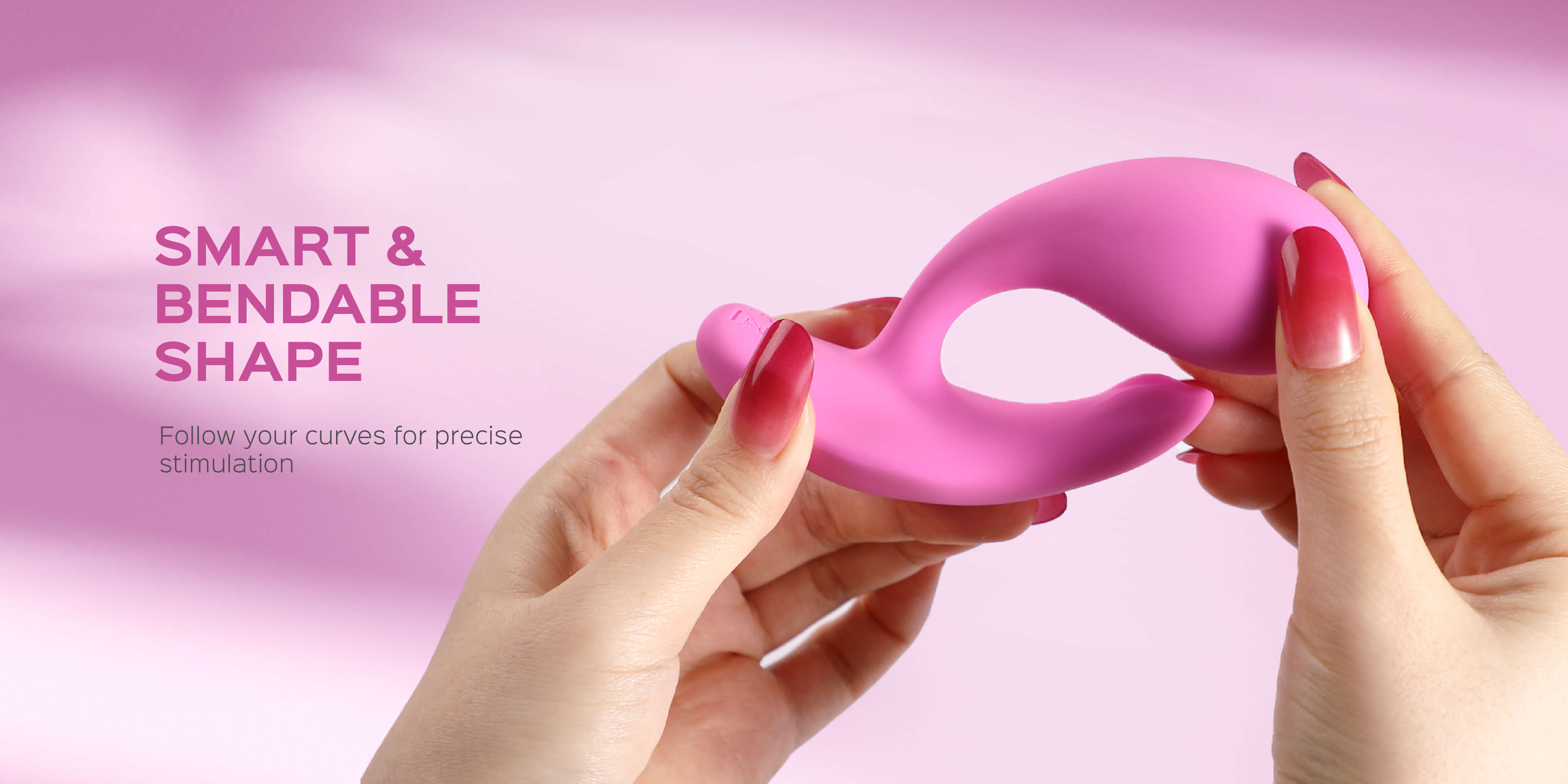 Pink bendable shape vibrator held by hands with a pink background