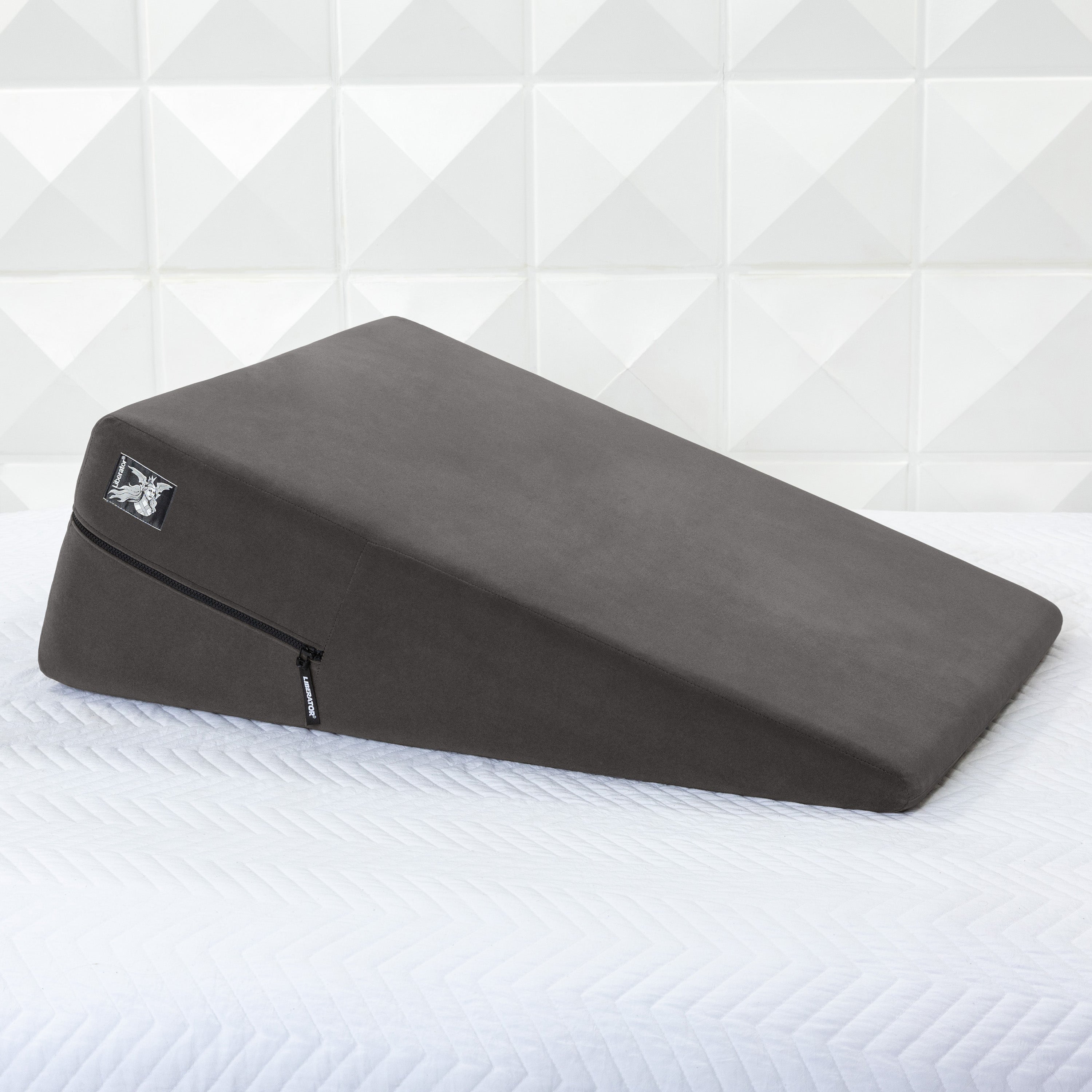 Gray ramp pillow on a white bed with geometric wall pattern