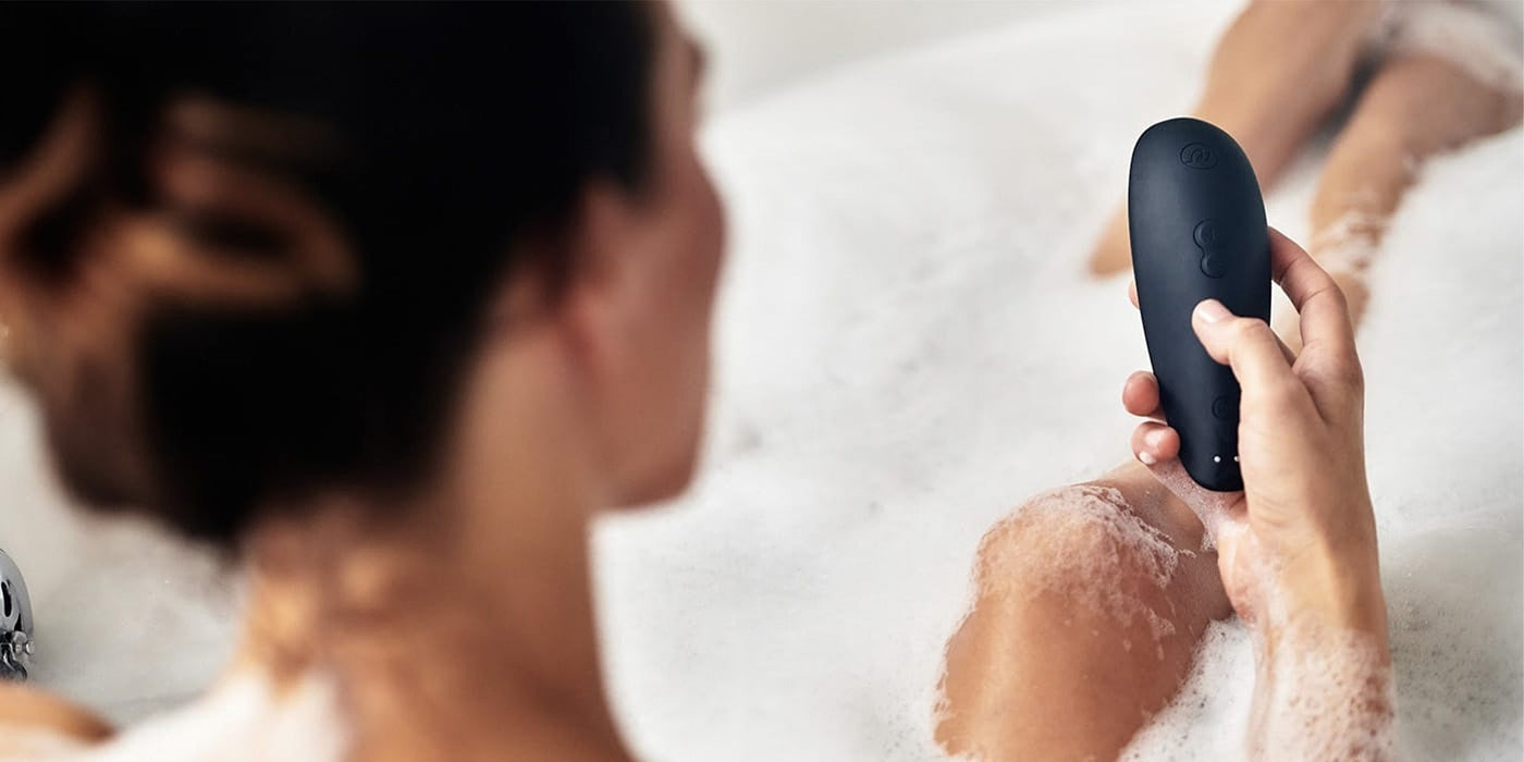 Woman in bath holding Womanizer toy