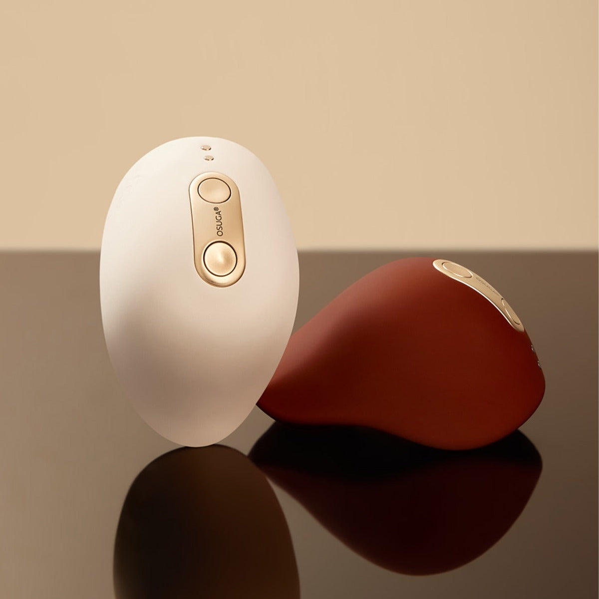 White and chocolate colors of the Kiss vulva tapping and heated vibrators by Osuga on sleek table