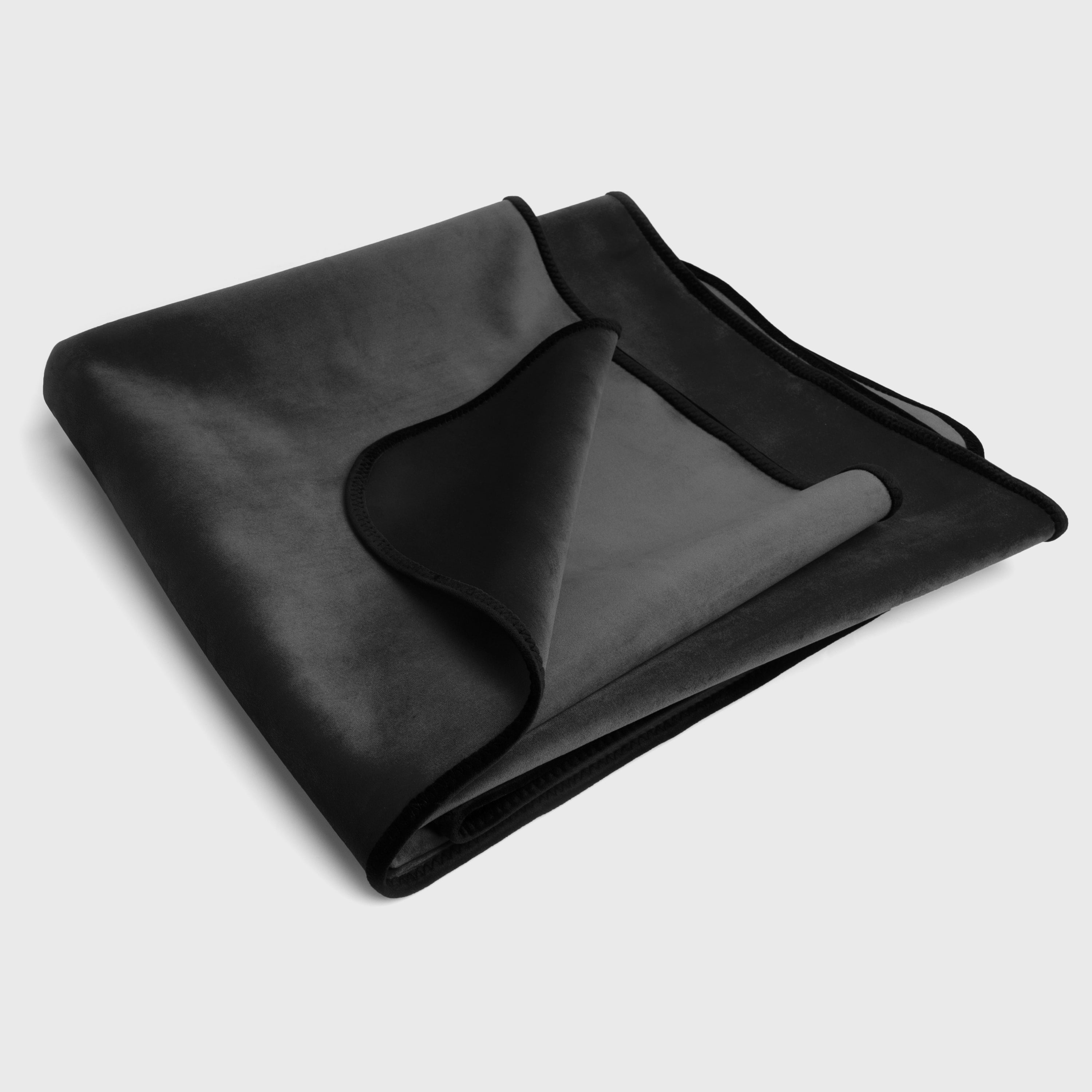 Folded black blanket on a light gray background