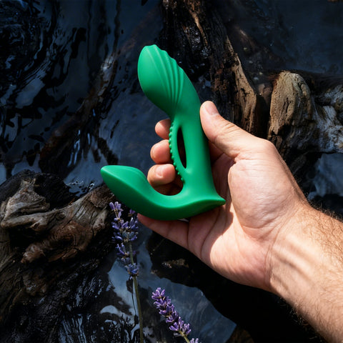 Hand holding a green massager near water and wood