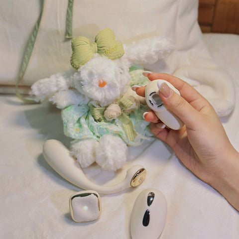 Hand holding a small plush toy with a white and green outfit on a light background