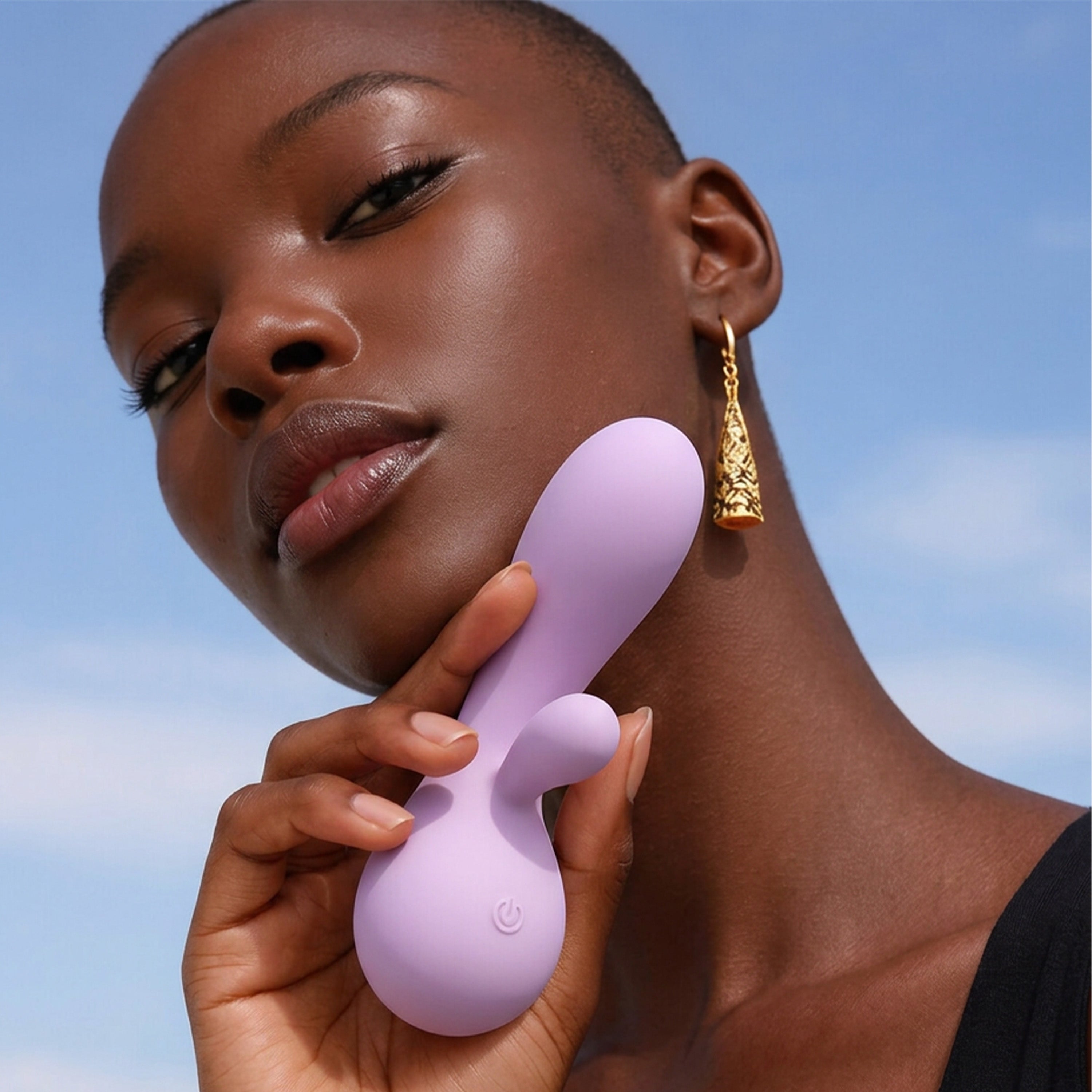 Woman holding a purple rabbit vibrator against a clear blue sky