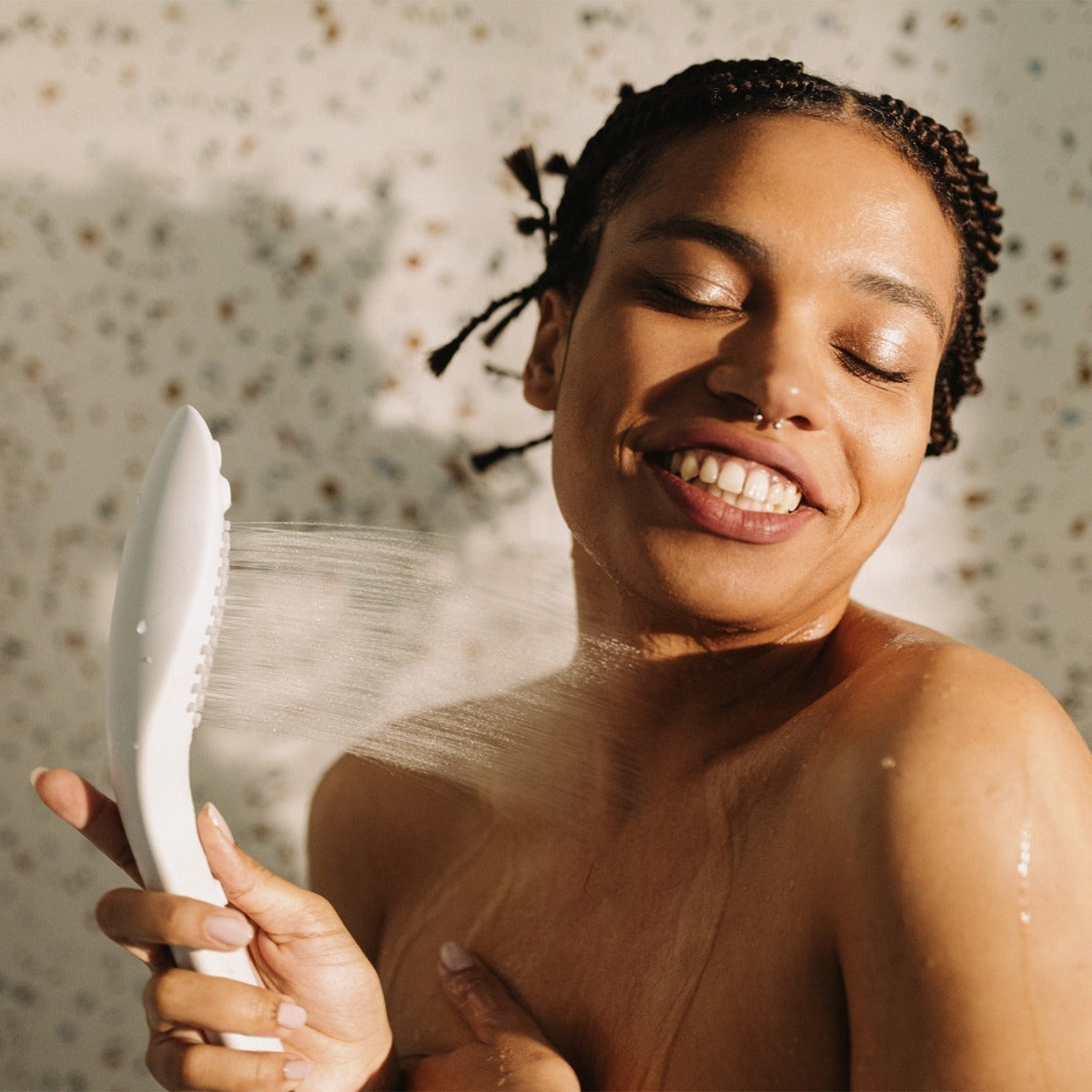 Woman holding a white showerhead with a blurred floral background