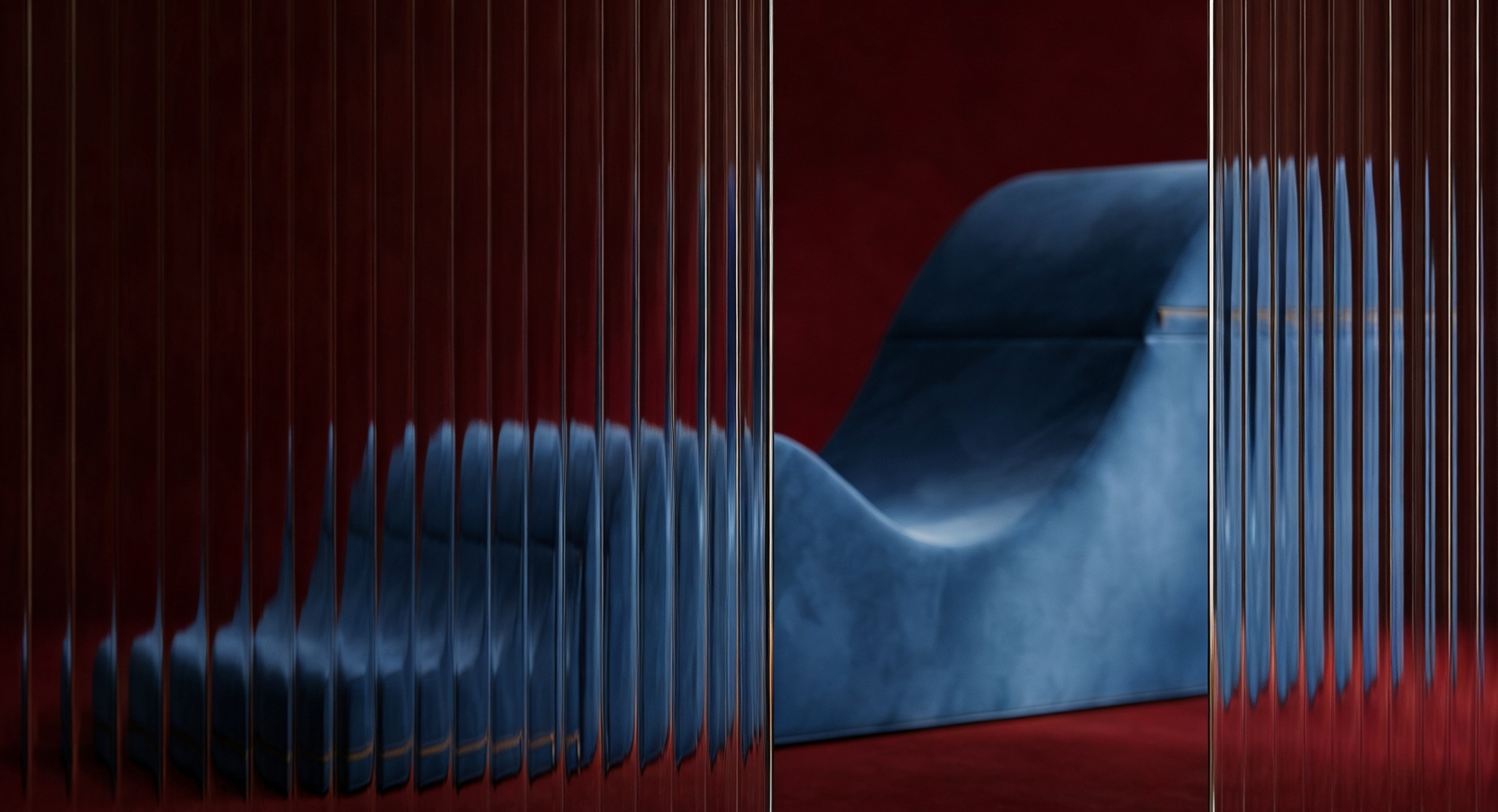 Blue Aria chaise on red background with slitted glass in the foreground