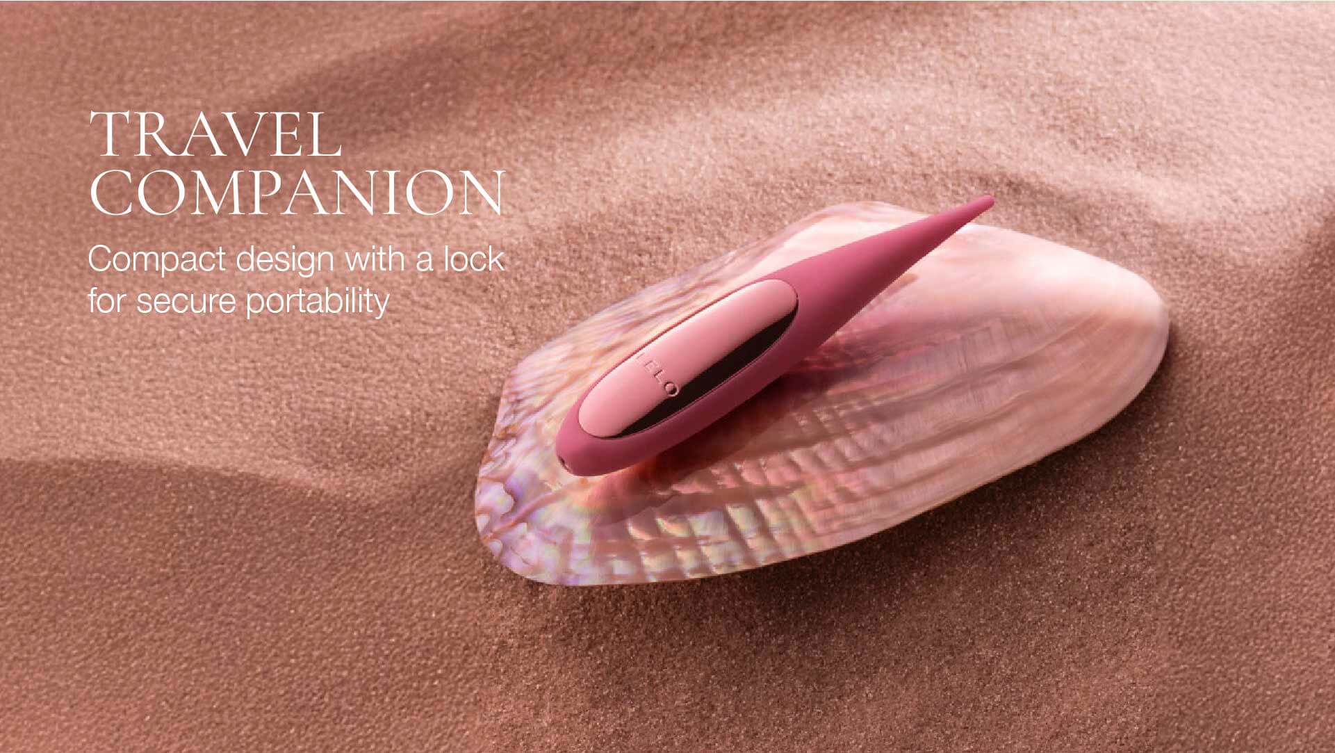 Compact pinpoint vibrator on a shell with sand background, labeled 'Travel Companion'.