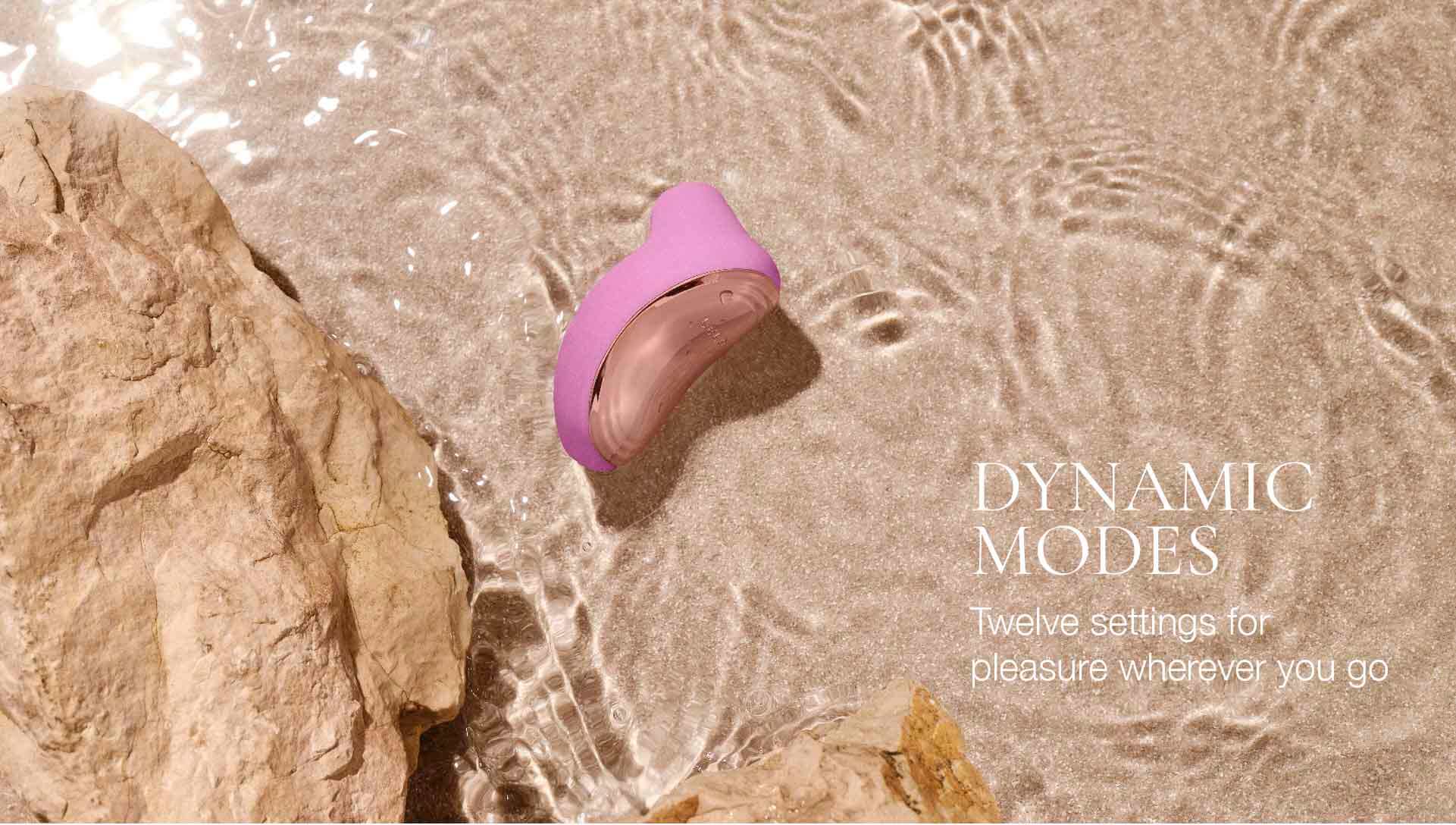 Pink electronic device on a beach with water and rocks