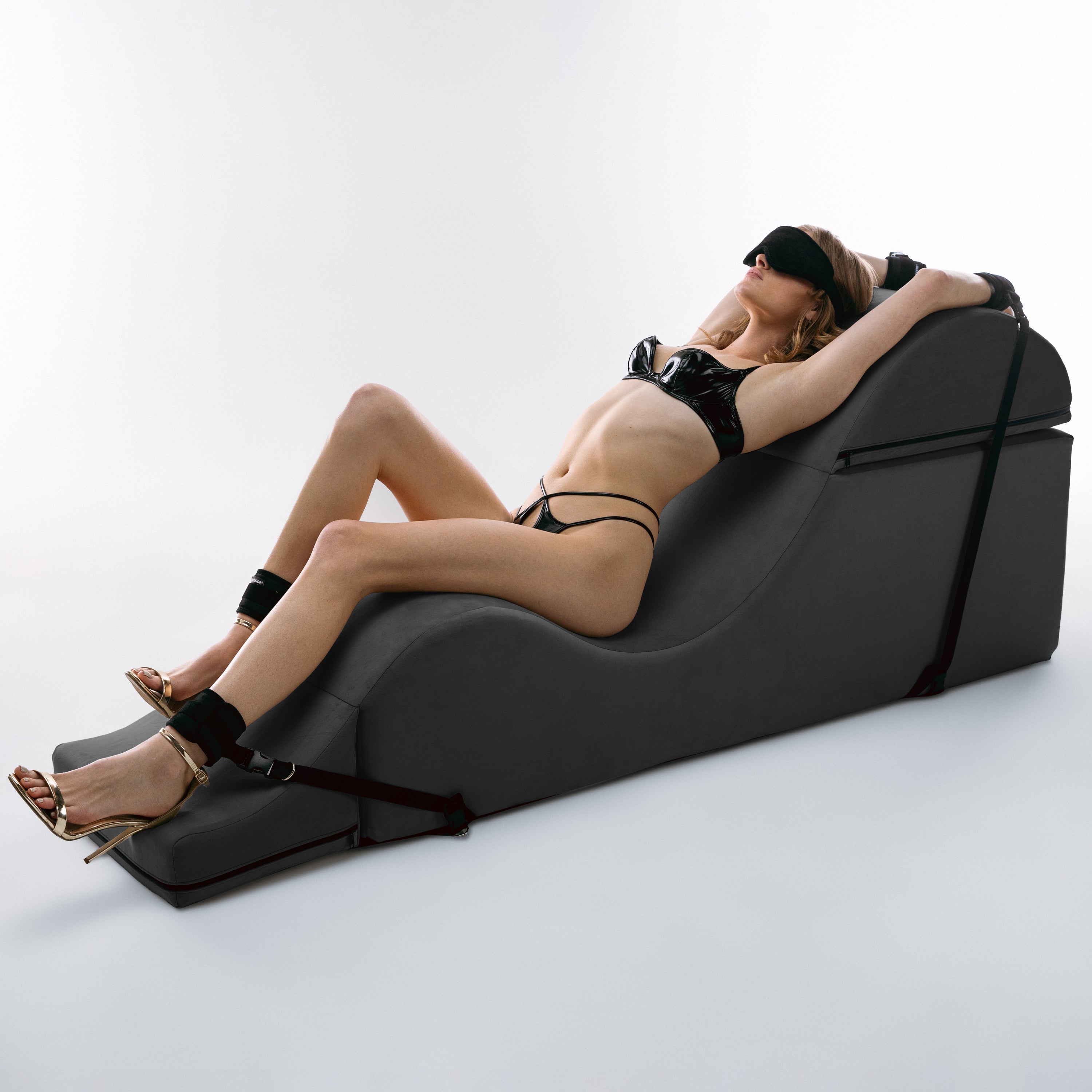 Woman relaxing in a modern black chaise on a white background
