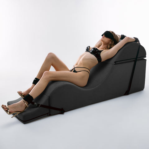 Woman relaxing in a modern black chaise on a white background