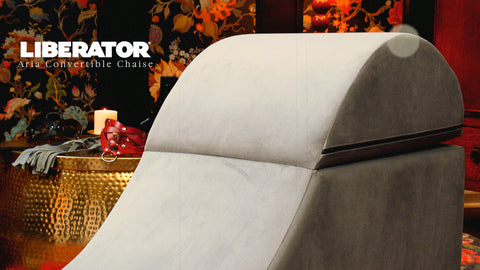 Gray convertible chaise with 'Liberator' branding against a decorative background.
