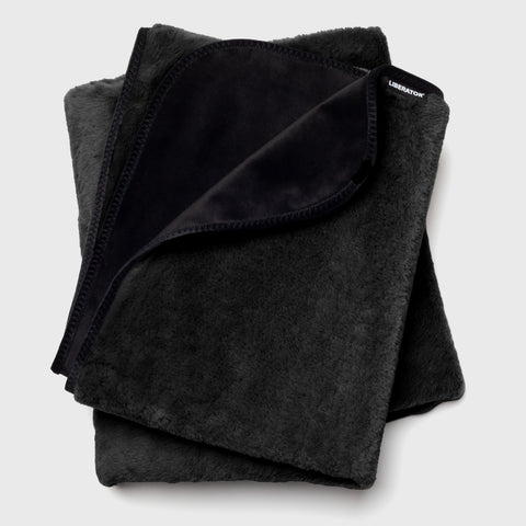 Folded black blanket with 'Liberation' branding on a light gray background