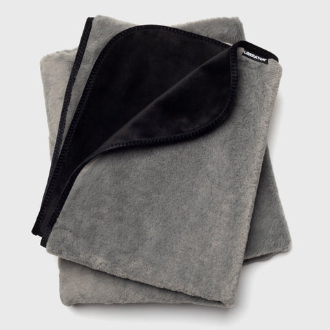 Folded gray blanket with black interior on a light gray background