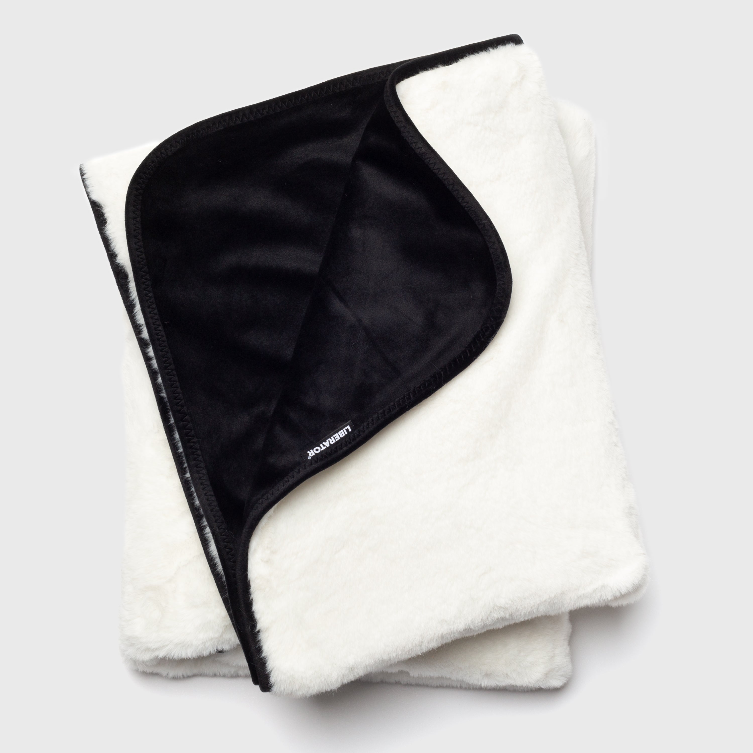 Folded white blanket with black interior on a light gray background