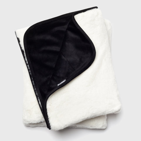 Folded white blanket with black interior on a light gray background