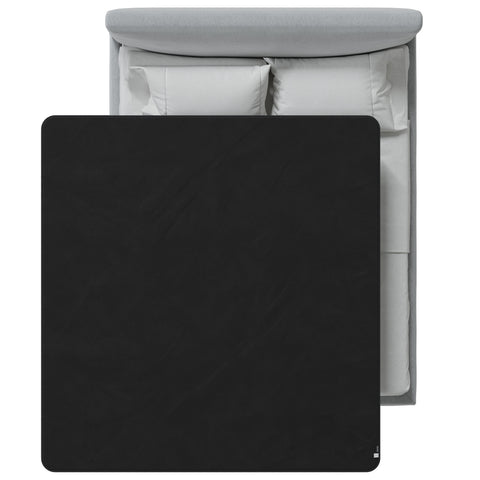 Black blanket on a bed with white bedding