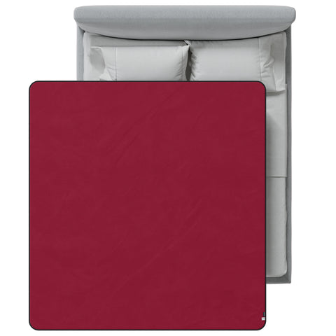 Red blanket on a bed with gray headboard and white pillows