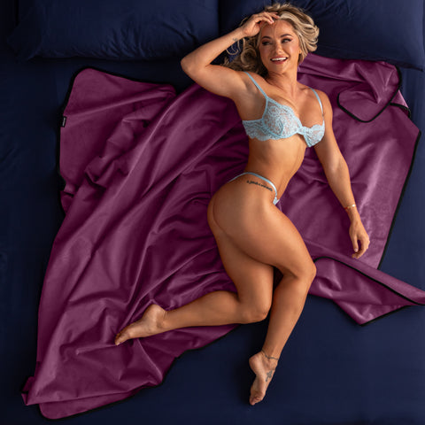 Woman in light blue lingerie lying on a purple blanket