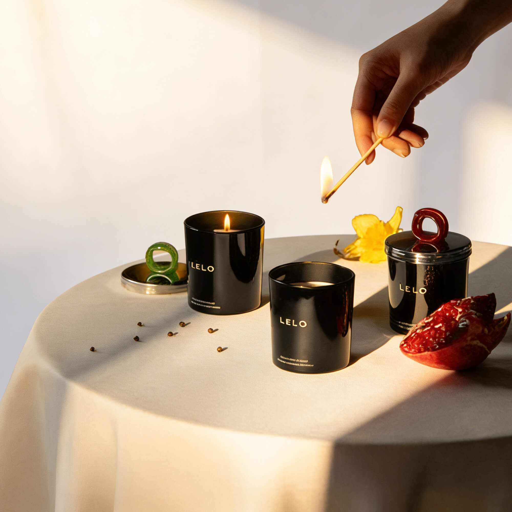LELO candles on a table with a hand lighting one of them.