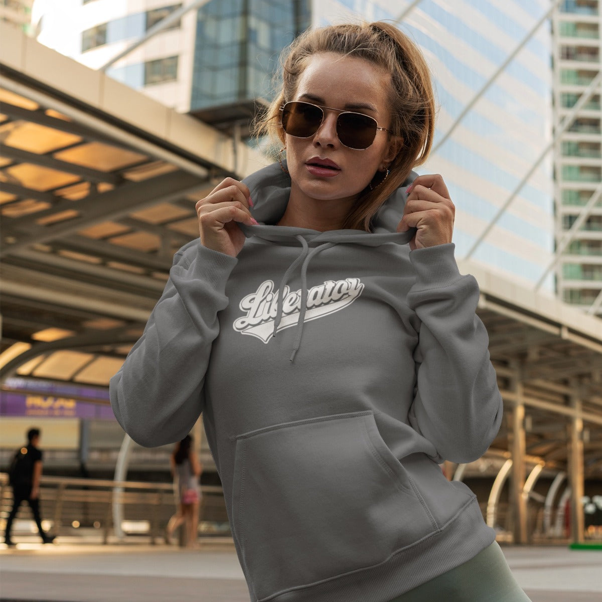 Woman showing off her Liberator Baseball Logo Hoodie, grey