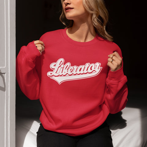 Woman wearing the red Liberator Baseball Logo Sweatshirt in her home