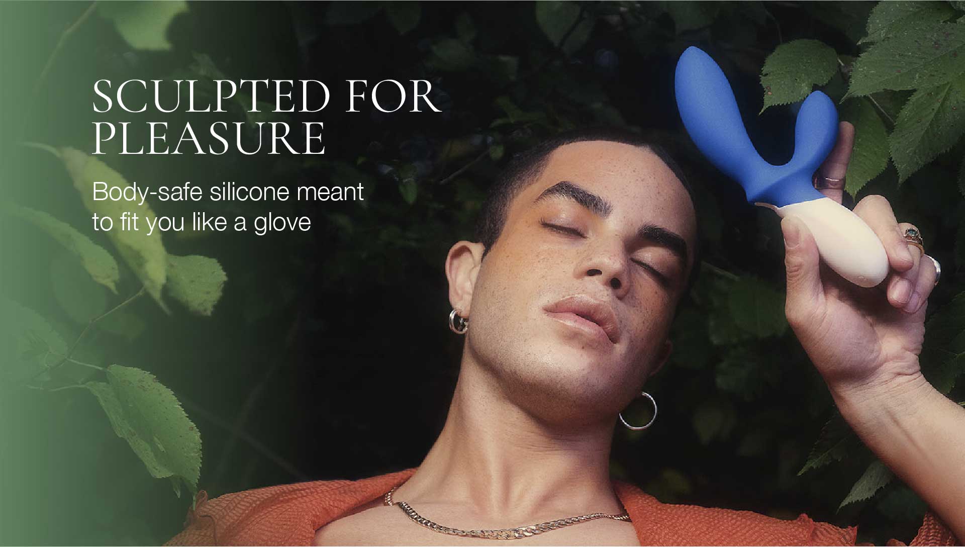 Person holding a blue and white silicone product with text 'Sculpted for Pleasure' against a green leafy background.