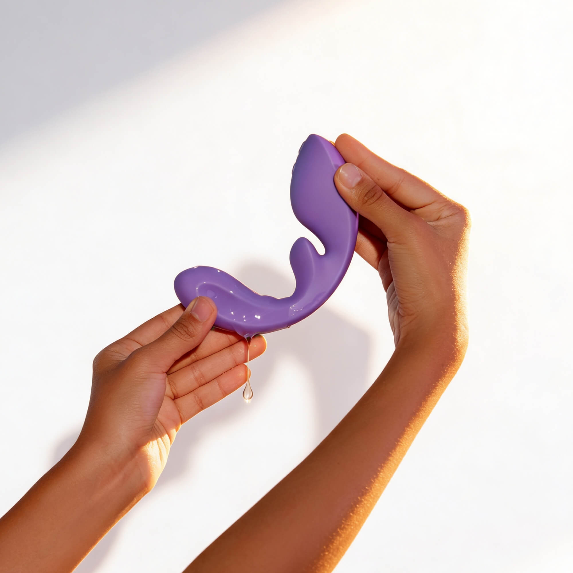 Purple silicone product held by hands against a white background