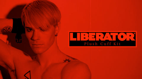 Person with tattoos and wrist cuffs against a red background with 'Liberator' branding.