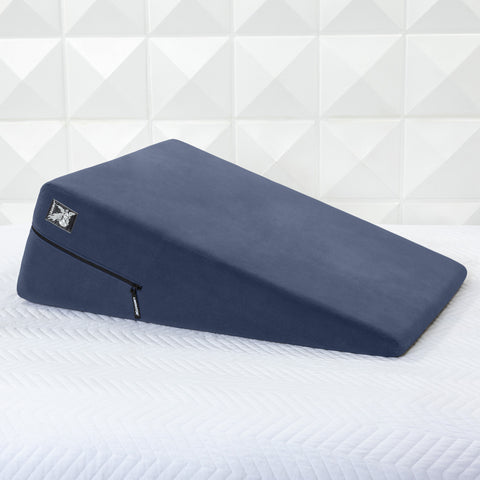 Blue ramp pillow on a white bed with geometric wall pattern