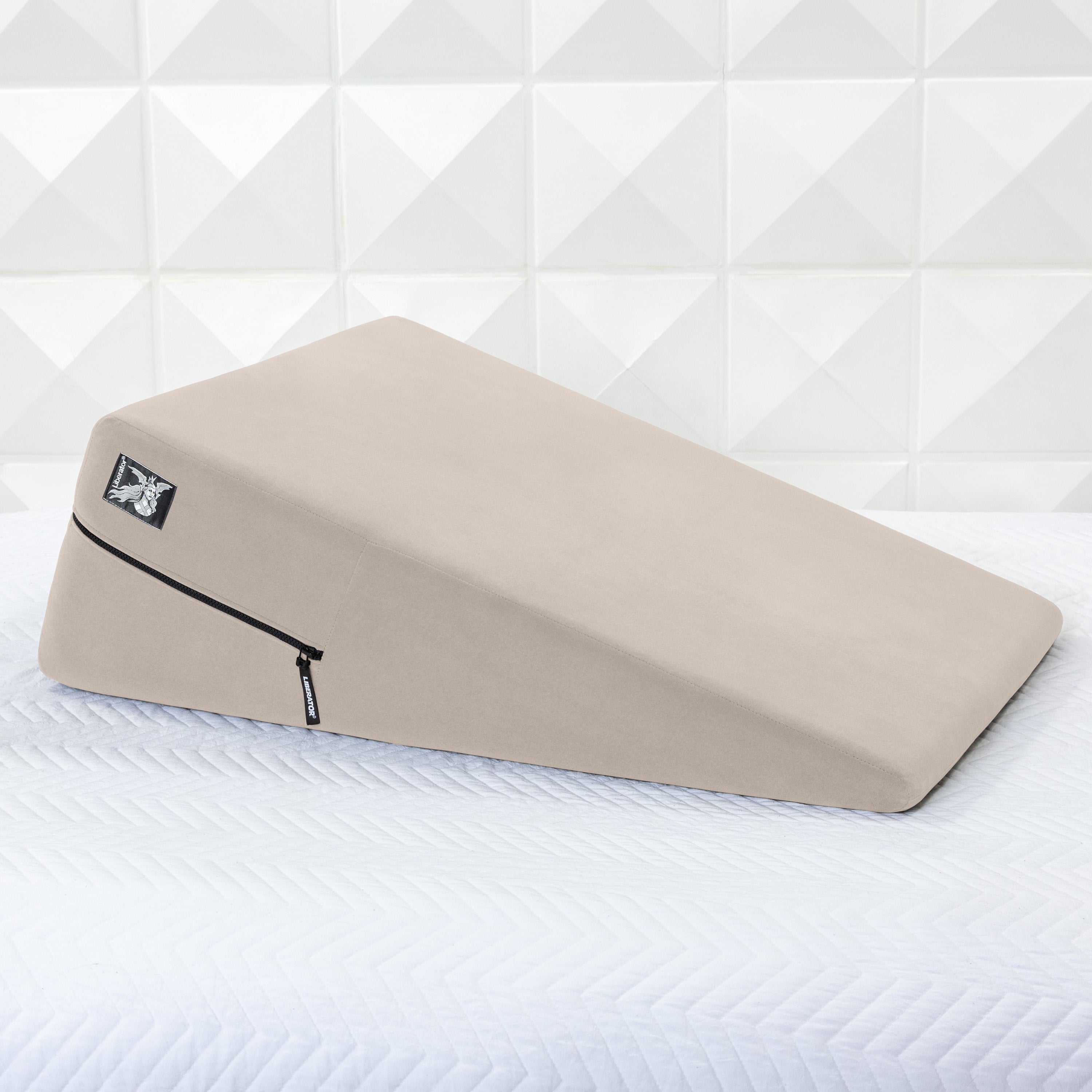 Beige ramp pillow on a white mattress with a geometric patterned wall in the background