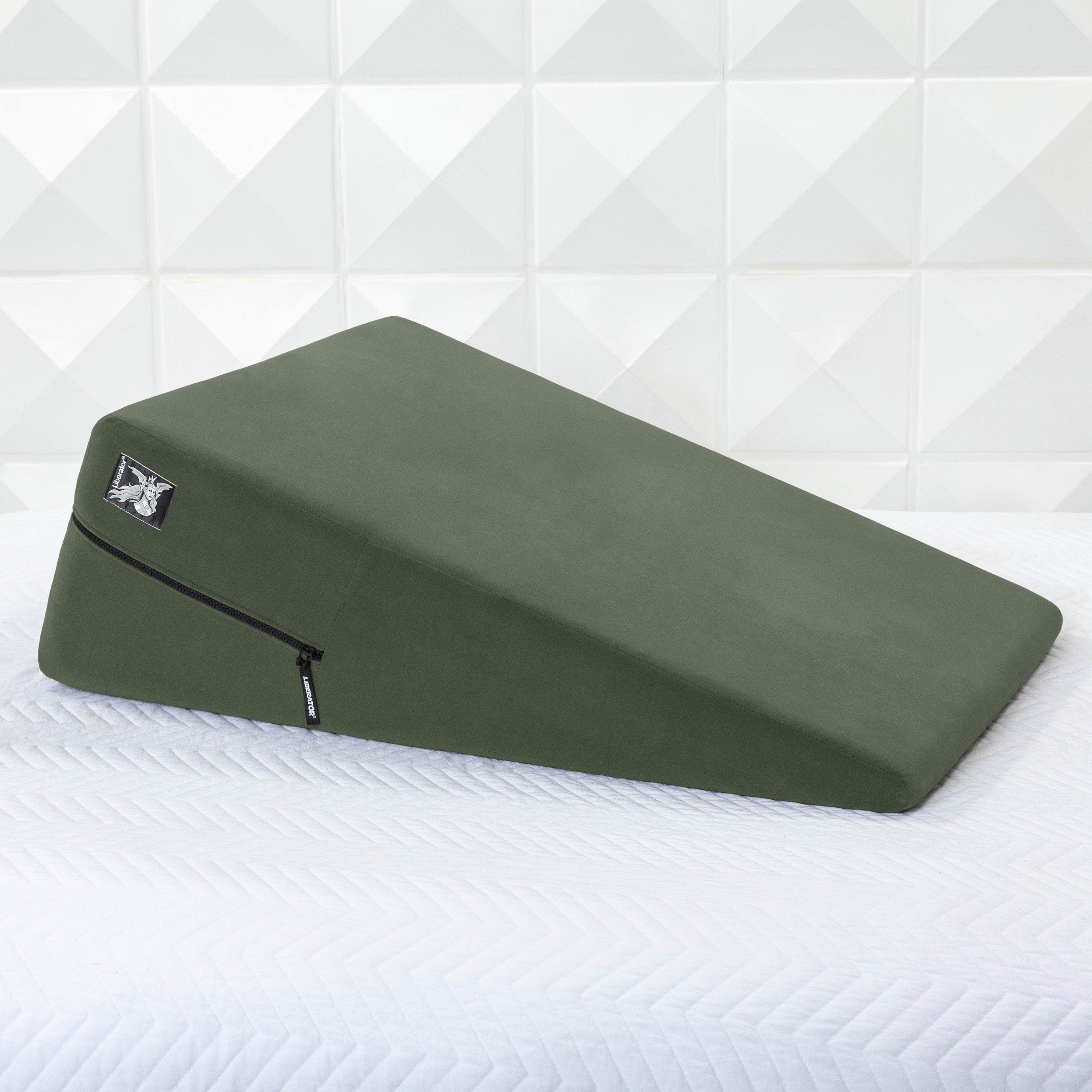 Green ramp pillow on a white bed with geometric wall pattern
