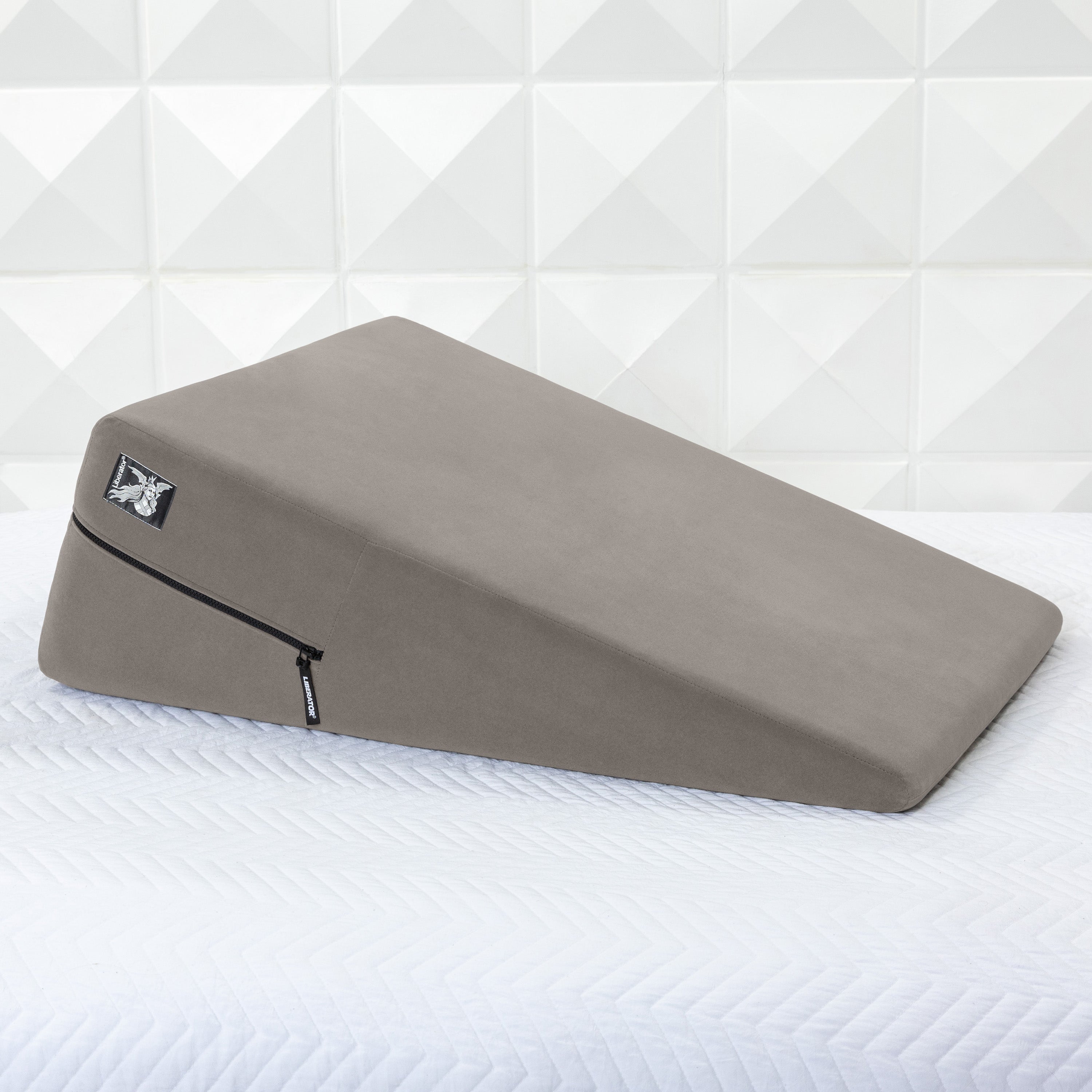 Gray ramp pillow on a white mattress with a geometric patterned wall in the background