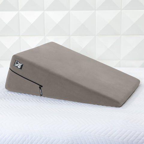 Gray ramp pillow on a white mattress with a geometric patterned wall in the background