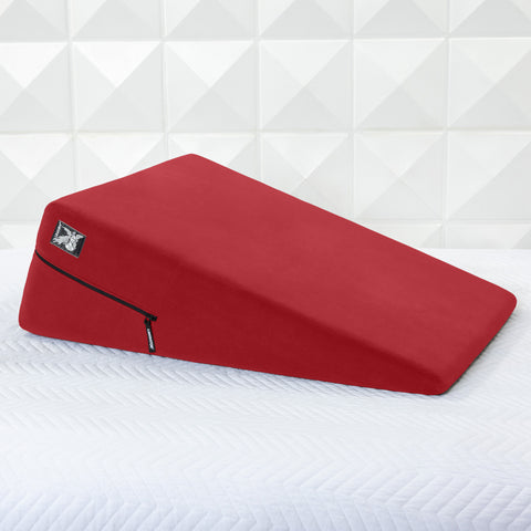 Red ramp pillow on a white mattress with a geometric patterned wall in the background