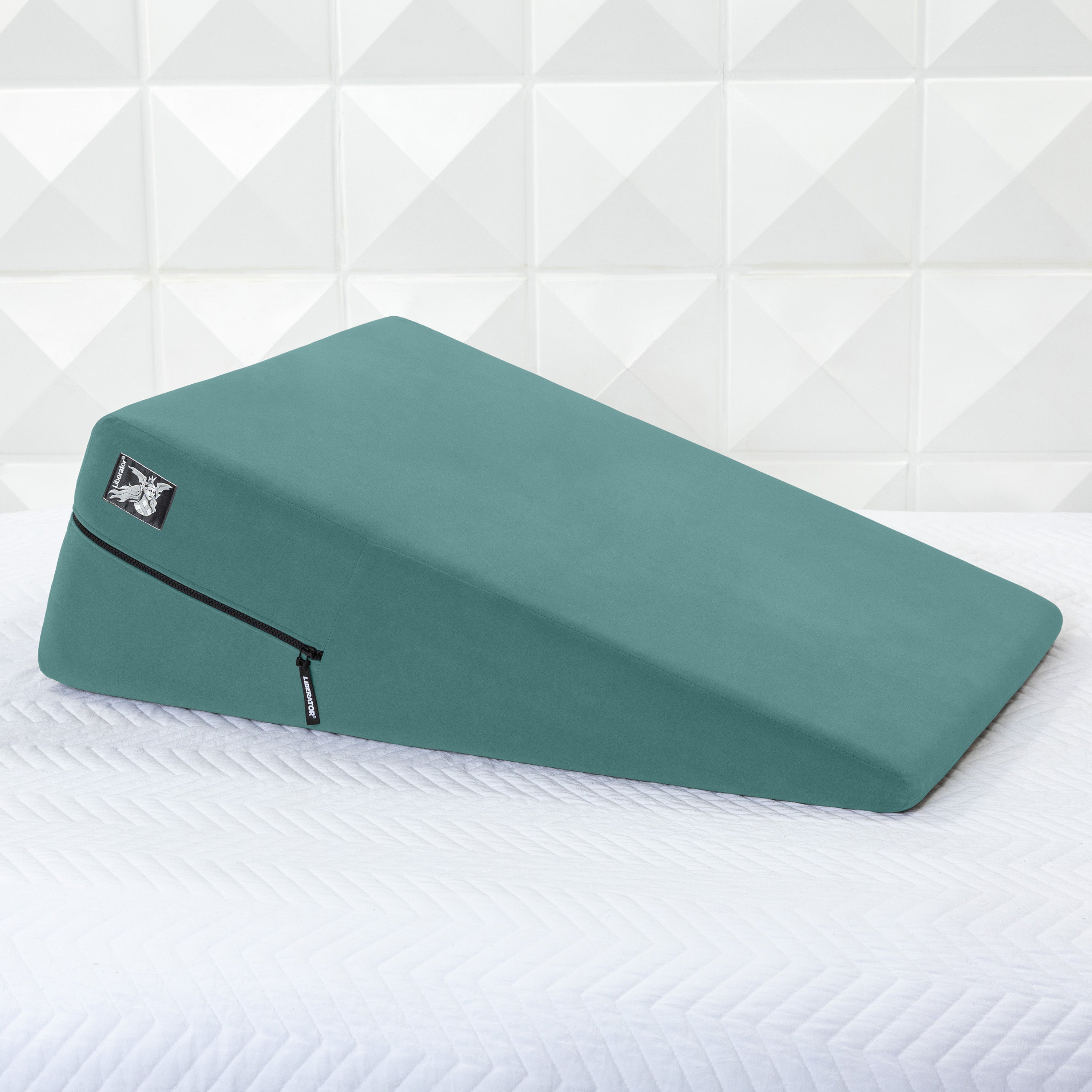 Green ramp pillow on a white mattress with a geometric patterned wall in the background