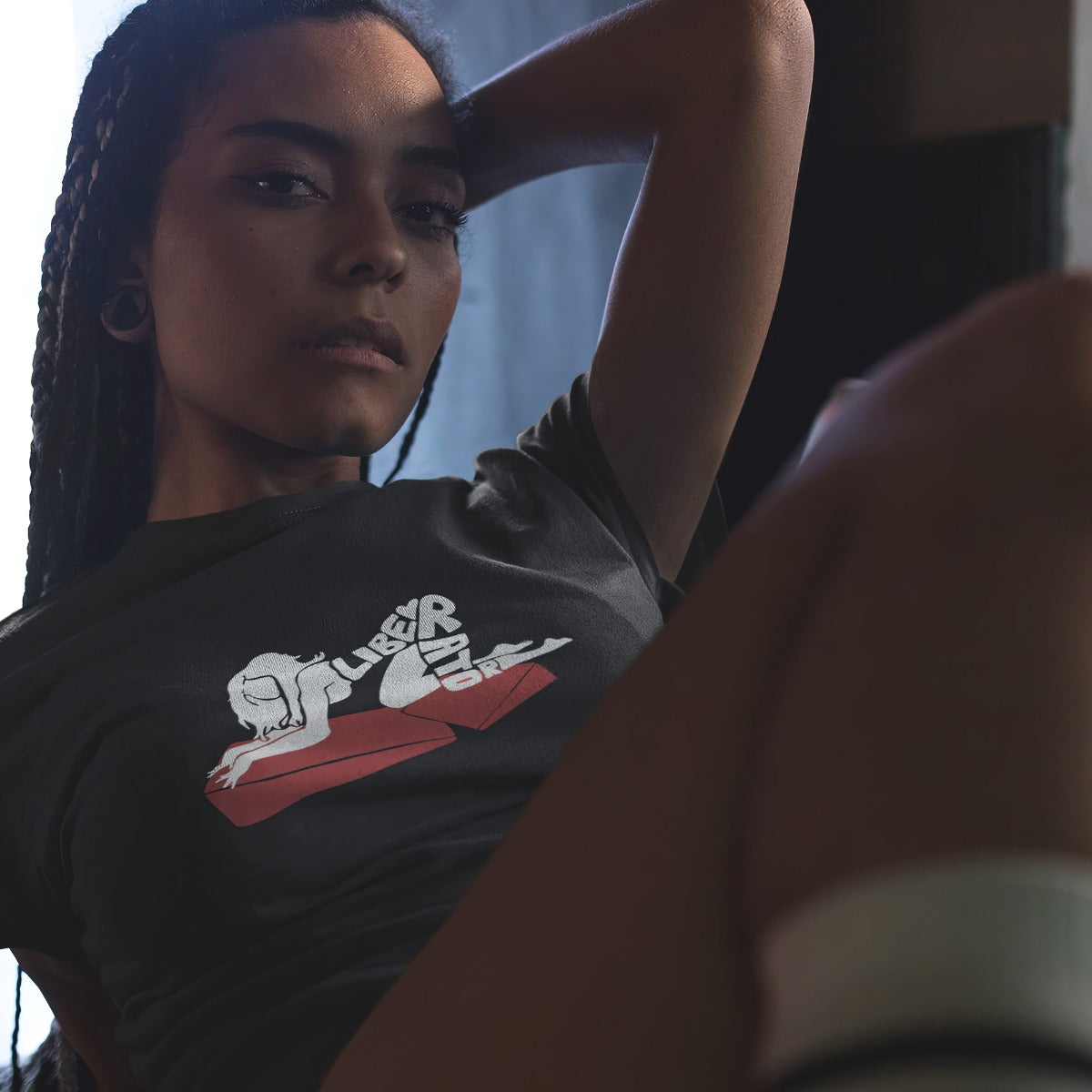 Woman laying back with her hand behind her head while she's wearing Liberator Merch Lady On A Combo t-shirt in black