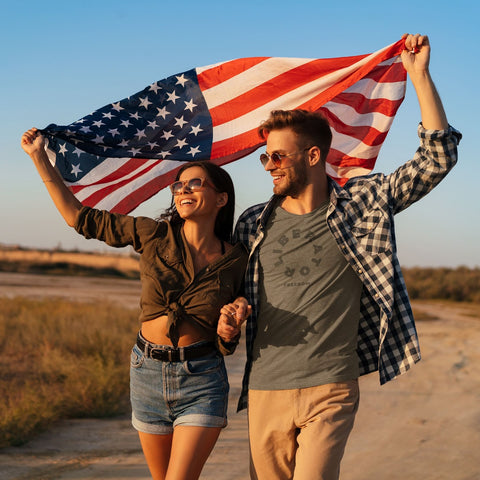Couple holding the American Flag higher while the man is wearing the Liberator Freedom Shirt