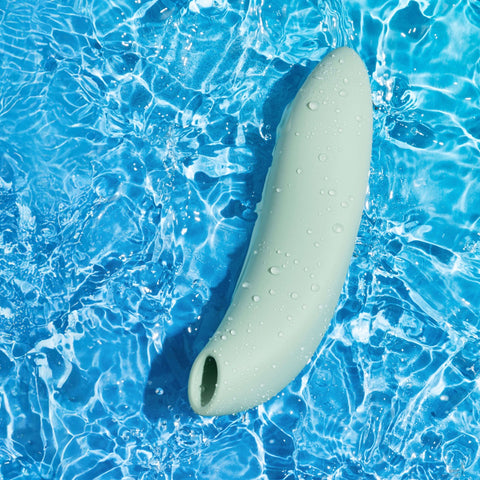 Lifestyle of sage green We-Vibe Melt 2 clitoral air stimulator sex toy for couples in blue water