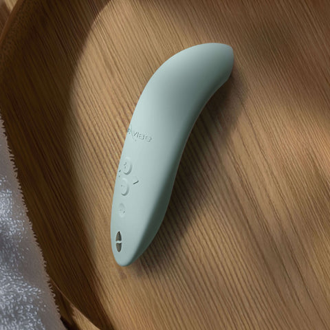 We-Vibe melt 2 in sage green lifestyle shot on tasteful wooden dish