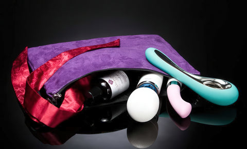Purple toy bag with red interior containing sexual products on a black background
