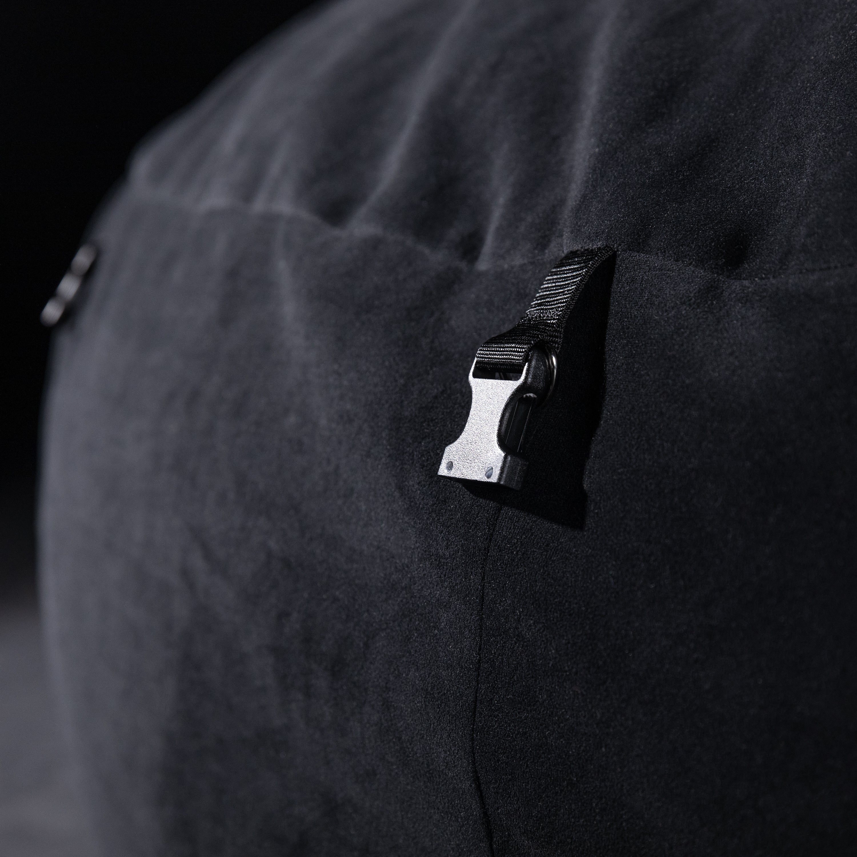 Close-up of a black clip on a dark fabric surface