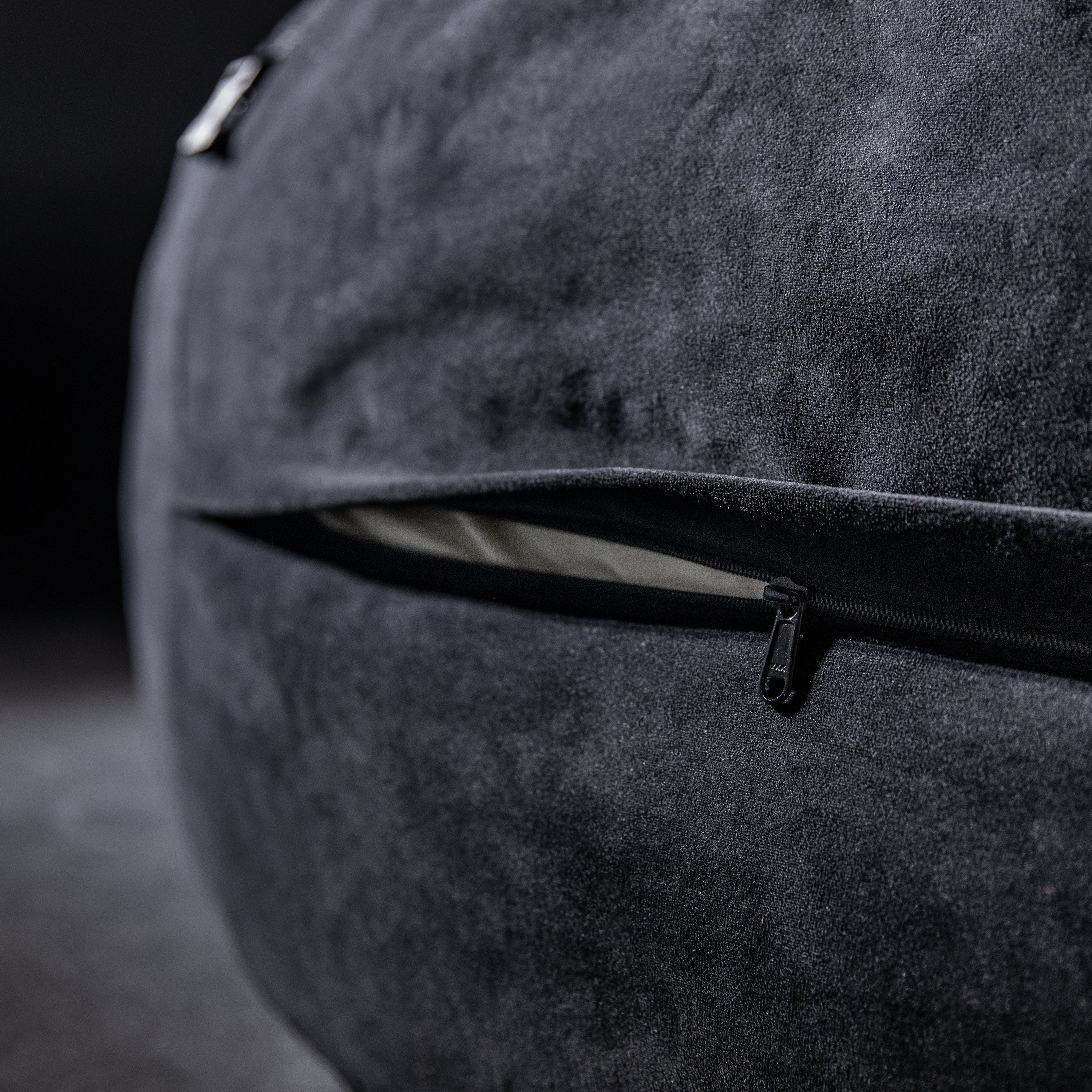 Close-up of a textured gray bag with a zipper on a dark background