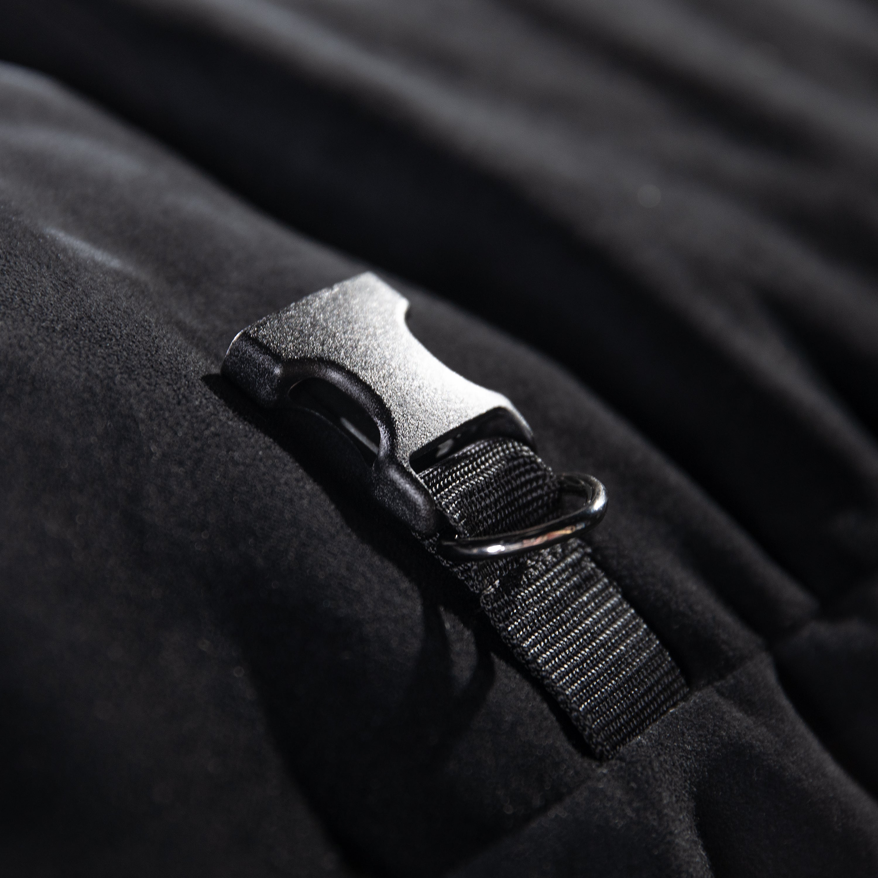 Close-up of a black strap with a plastic buckle on a dark fabric background