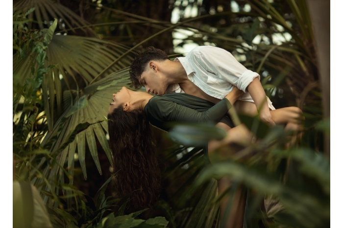 Man carrying woman bridal style surrounded by thick foliage