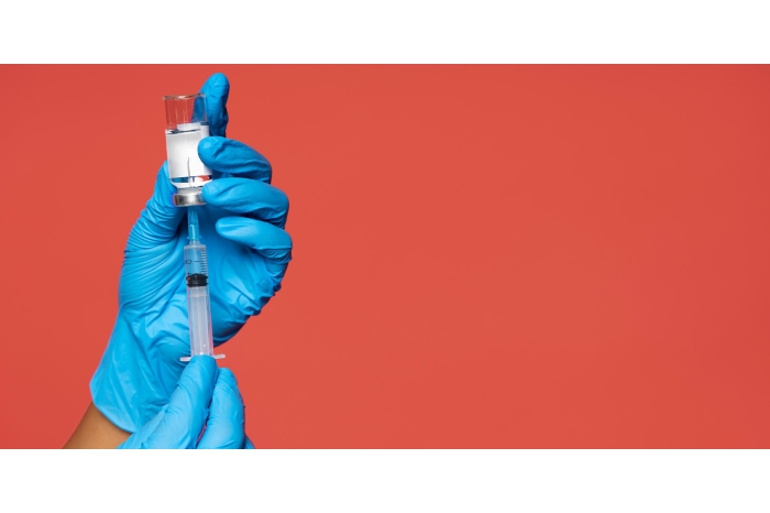 Person with sterile gloves withdrawing a vaccine solution