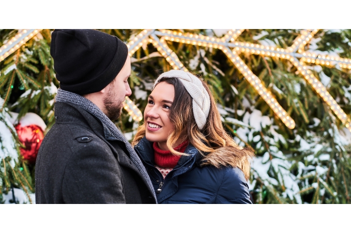 Couple standing together in warm clothing at Christmas tree farm